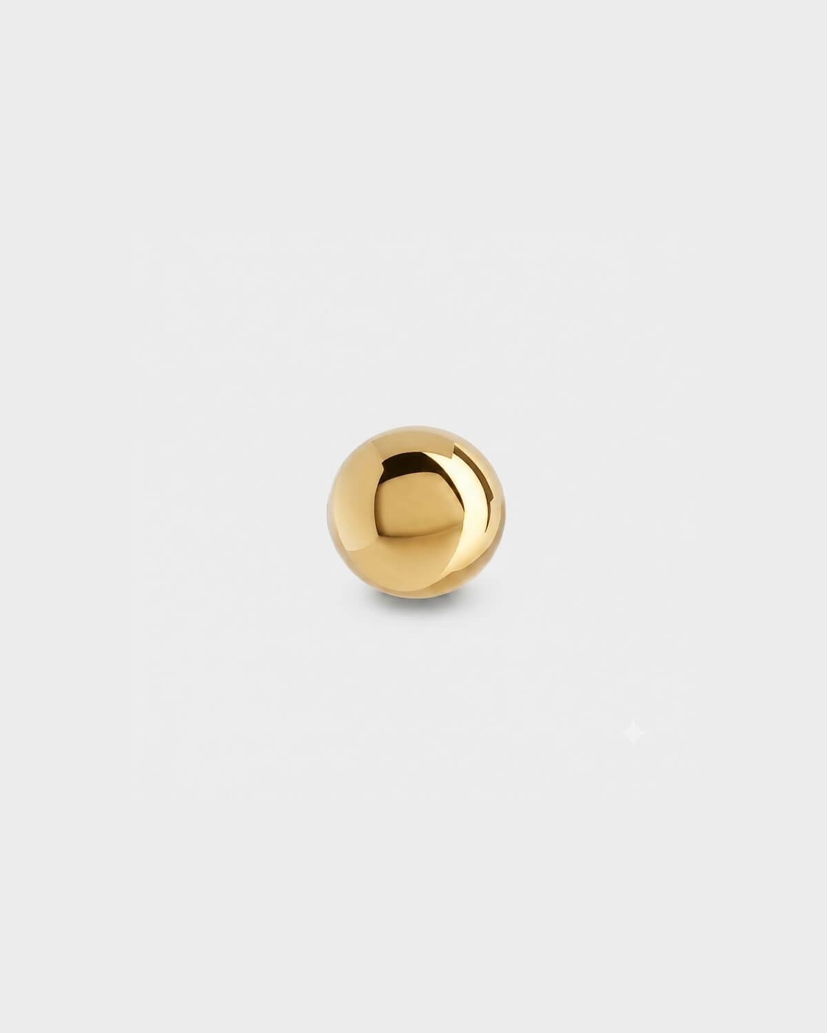 Plain gold titanium ball for piercing jewellery on a light grey background