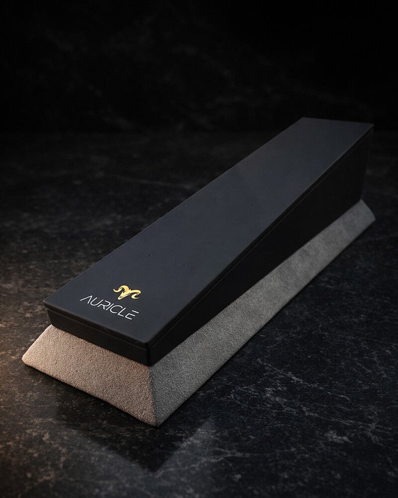 jewellery display stand to hold 20 pieces of jewellery. The stand has a light gray suede base with a black leather top. Sat on a dark worktop with moody lighting.