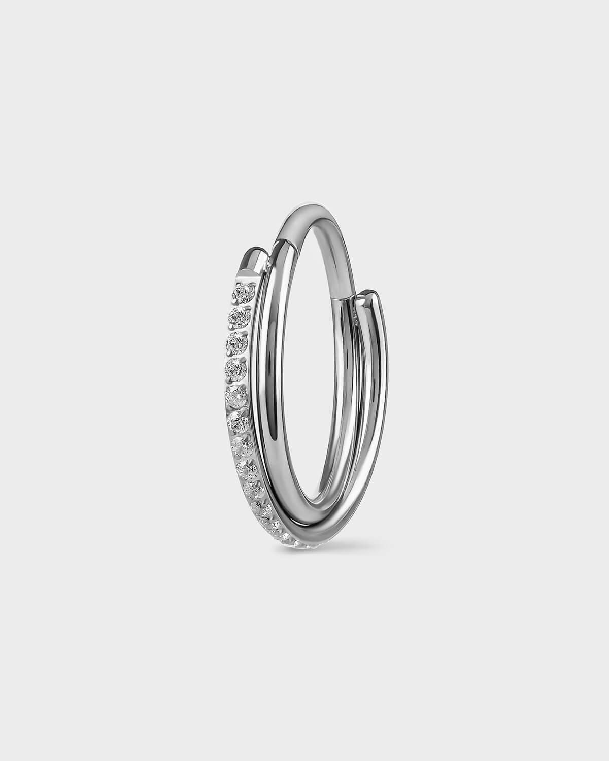 Polished silver titanium with double twist ring. One pave and the other plain. Clear gemstones. Sat on a light gray backround.