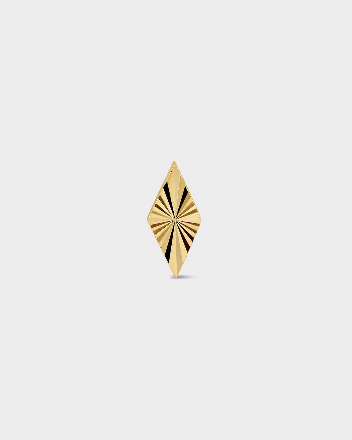 Diamond shape gold earring with laser engraved lines on a light ray background