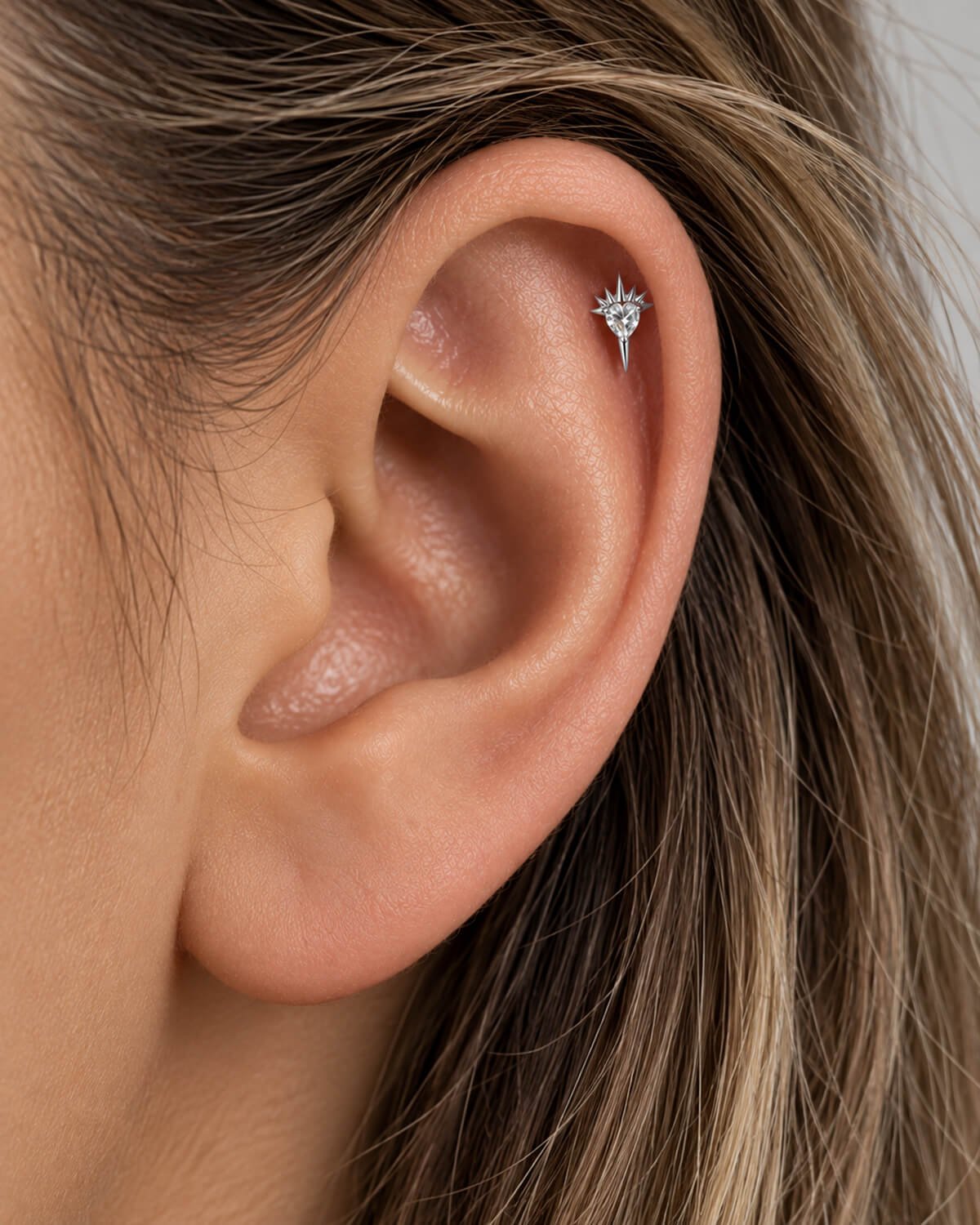woman woman with helix piercing wearing sacred earring by auricle.