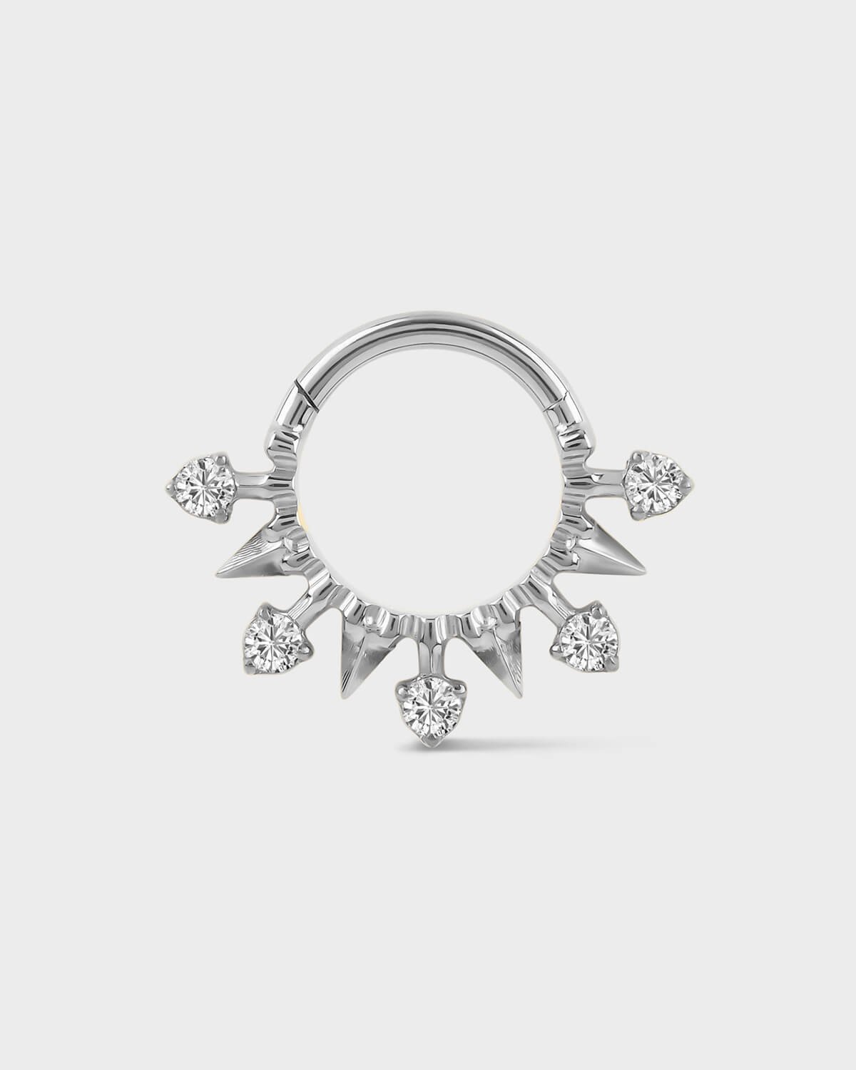 Polished silver titanium daith or septum ring with alternating spikes and solitaires on a light gray background.